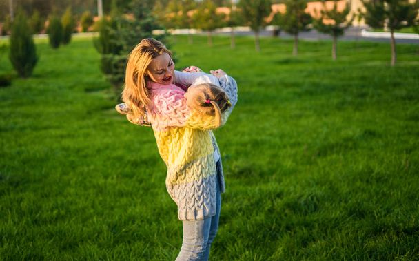 Szczęśliwa rodzina. Matka bawi się z córką na zielony trawnik z trawy - Zdjęcie, obraz