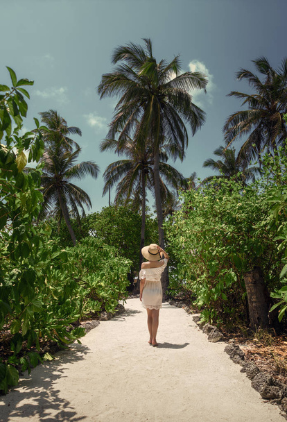 A girl in a white dress under the palm trees. Maldives. Vacation. Recreation. Tropics. - 写真・画像