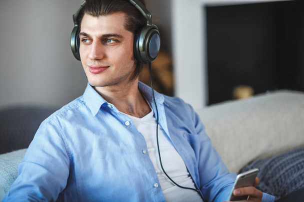 Handsome guy sitting on sofa with headphones - Foto, immagini