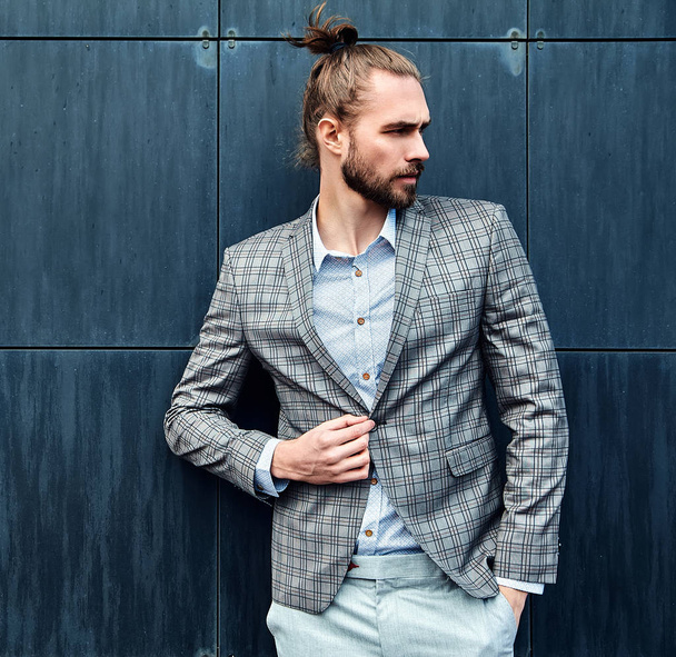 portrait of sexy handsome fashion male model man dressed in elegant checkered suit posing outdoors on the street background - Foto, imagen
