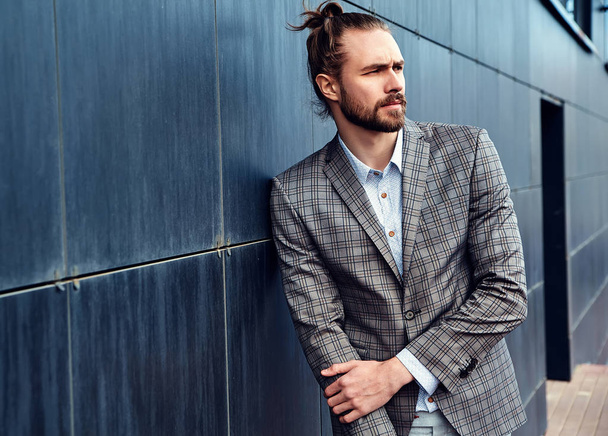portrait of sexy handsome fashion male model man dressed in elegant checkered suit posing outdoors on the street background - Fotó, kép