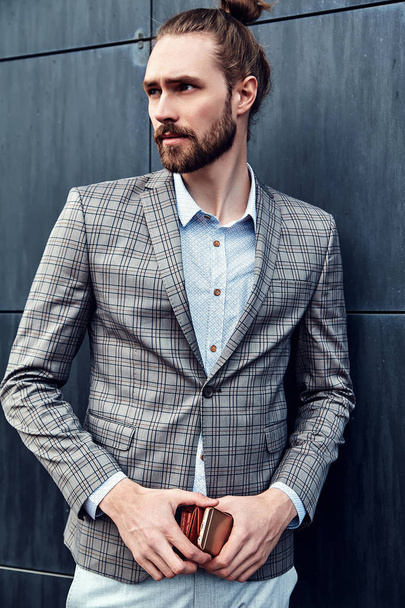 portrait of sexy handsome fashion male model man dressed in elegant checkered suit posing outdoors on the street background - Foto, afbeelding