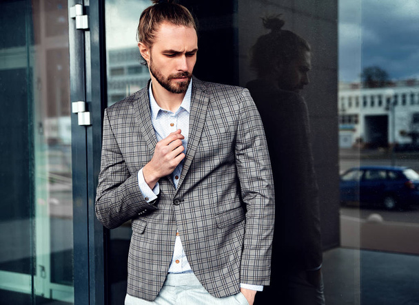 portrait of sexy handsome fashion male model man dressed in elegant checkered suit posing outdoors on the street background - Foto, Bild