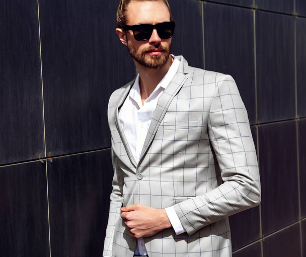 portrait of sexy handsome fashion male model man dressed in elegant checkered suit posing outdoors on the street background - Zdjęcie, obraz