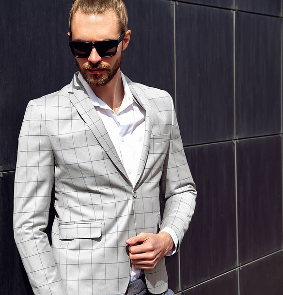 portrait of sexy handsome fashion male model man dressed in elegant checkered suit posing outdoors on the street background - Foto, immagini