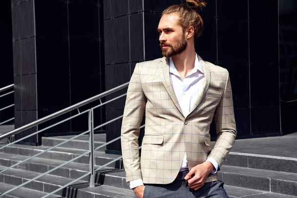 portrait of sexy handsome fashion male model man dressed in elegant checkered suit posing outdoors on the street background - Foto, Imagen