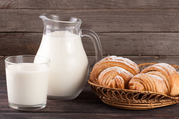 кувшин и стакан молока с круассанами на деревянном фоне
 - Фото, изображение