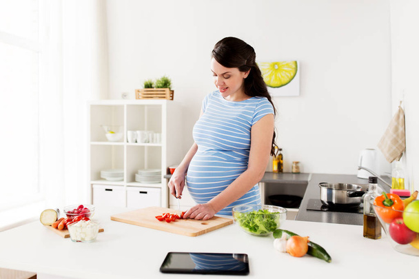 mujer embarazada cocinar verduras en casa
 - Foto, imagen