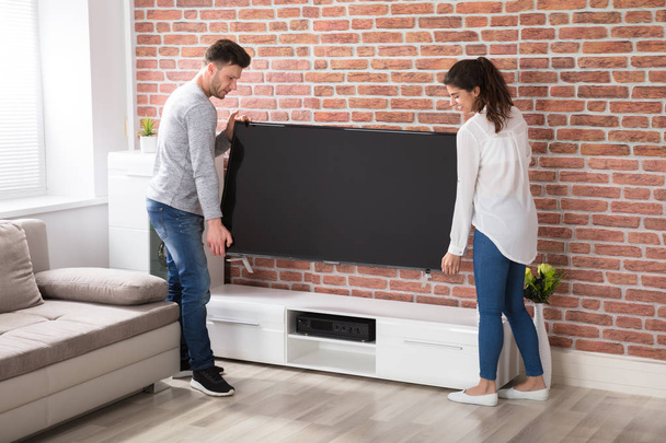 couple carrying new tv set at home - Фото, изображение