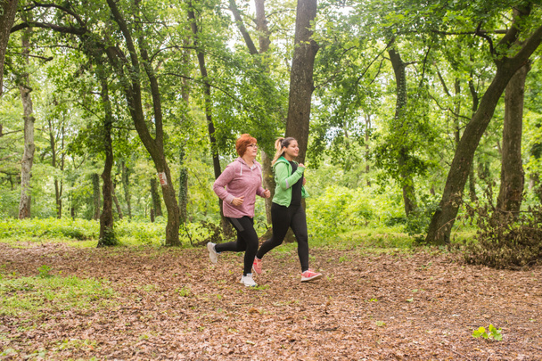 Matka a dcera nosí sportovní oblečení a běh v lese na  - Fotografie, Obrázek