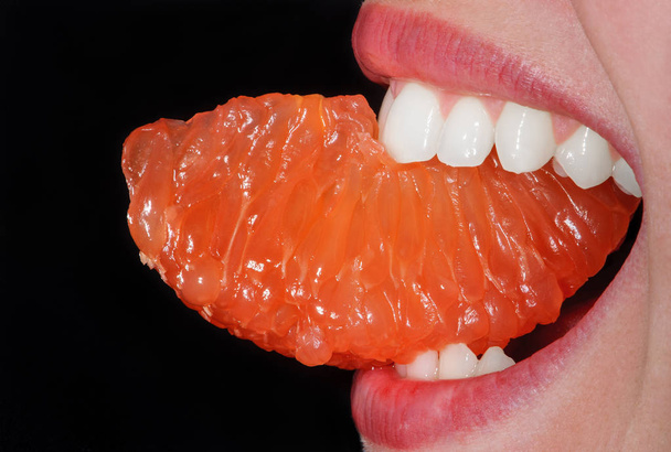 Gros plan orange dans la bouche de la femme
  - Photo, image