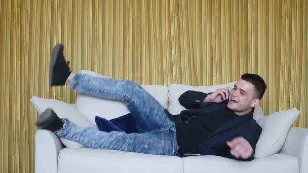 man using a smartphone, lying on the couch - Filmati, video