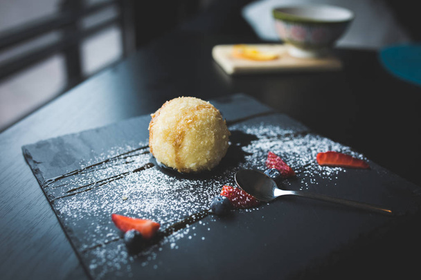 Grilled ice-cream in coconut with sauce on black stone plate. Asian food background. Eating concept. Restaurant place with wooden table. Copy space for text, design. - Photo, image