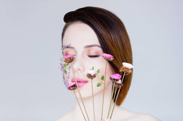 beautiful young woman with flowers on cheeks - Photo, Image