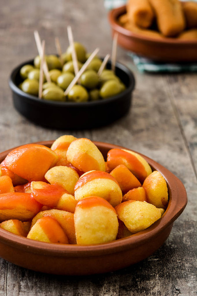 Traditional spanish tapas. Croquettes, olives and patatas bravas on wooden table - 写真・画像