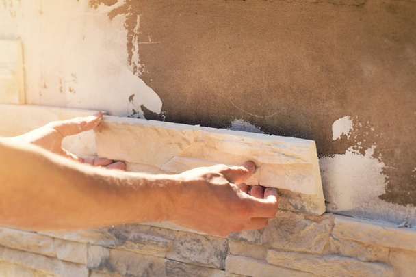 працівник встановлює декоративну кам'яну плитку на фасад будинку
 - Фото, зображення