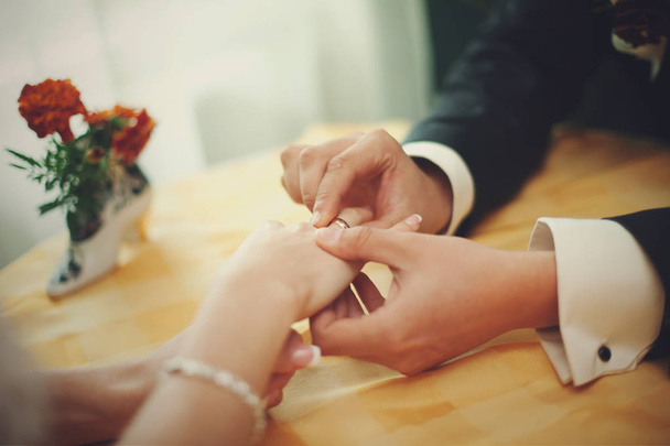 Man adjusts a ring on delicate bride's hand - Fotó, kép