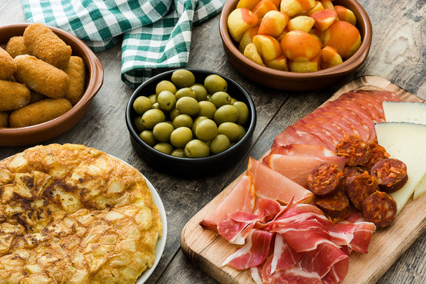 Tradiční španělská tapas. Krokety, olivy, omeleta, šunka a patatas bravas na dřevěný stůl - Fotografie, Obrázek