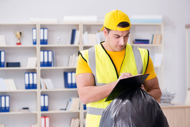 Homem limpando o escritório e segurando saco de lixo - Foto, Imagem