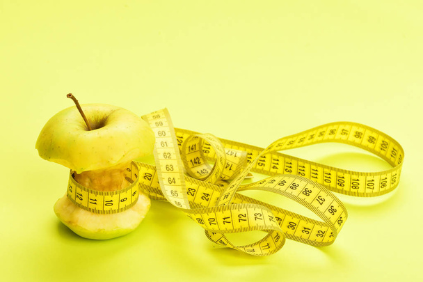 Apple wrapped by yellow measure tape - Foto, Imagen