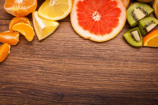 lemon, orange, kiwi, grapefruit, mandarin on a wooden surface. arrangement of sliced fruit. Top view with copy space for text - Foto, Imagem