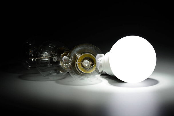 Glowing led lamp and incandescent bulbs in the dark - Photo, Image
