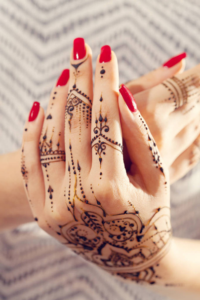 Red manicured hands with Mehndi  - Foto, afbeelding