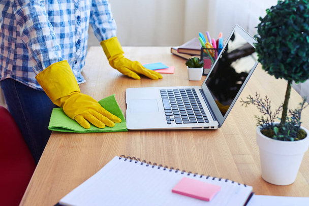 Woman dusting desk near laptop - Photo, Image