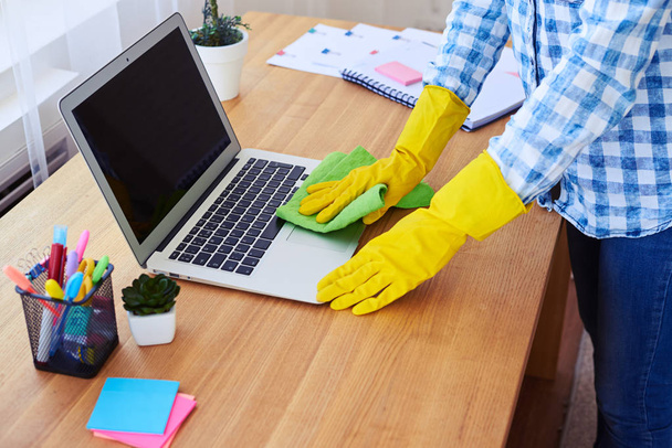 Hausfrau in Handschuhen staubt Laptop ab - Foto, Bild