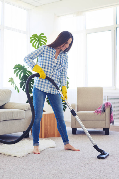 Skinny brunette cleaning with vacuum cleaner carpet - Foto, Imagen