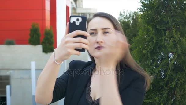 Beautiful woman checking her makeup and hair using camera of smartphone before taking selfie - Кадри, відео