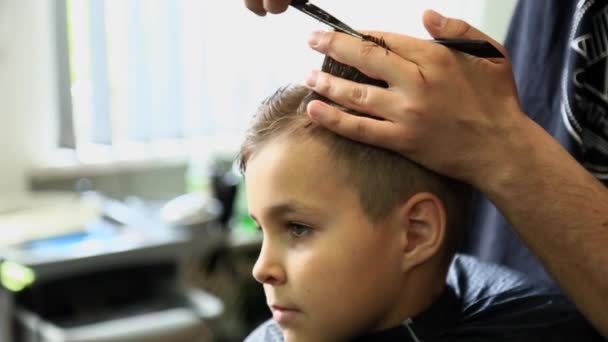 Mały chłopiec coraz fryzura Barber, siedząc w fotelu na fryzjera. - Materiał filmowy, wideo