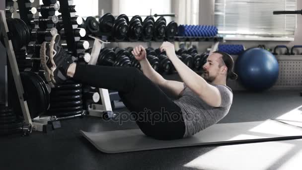 Muskularny mężczyzna robi siedzieć ups w siłowni - Materiał filmowy, wideo