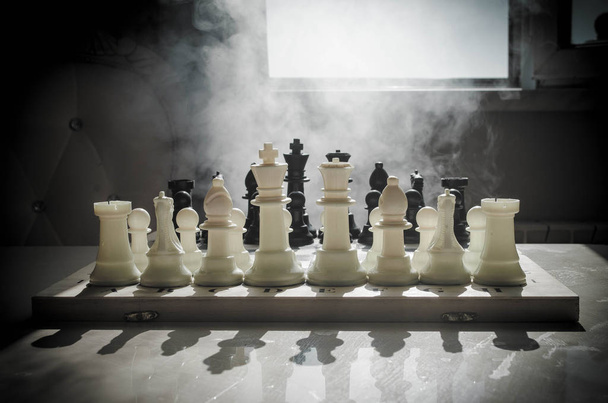 Schaken bordspel concept van bedrijfsideeën en concurrentie en strategie ideeën concep. Chess cijfers op een donkere achtergrond met rook en mist. Selectieve aandacht. Hand zet figuur aan boord - Foto, afbeelding
