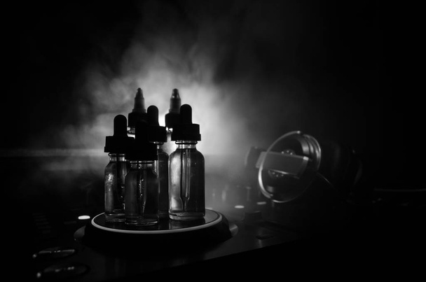 Vape- und DJ-Clubkonzept. Rauchwolken und Dampfflaschen am DJ-Mixer aus nächster Nähe. Lichteffekte. nützlich als Hintergrund oder Vape oder Club Werbung oder Vape Hintergrund. - Foto, Bild