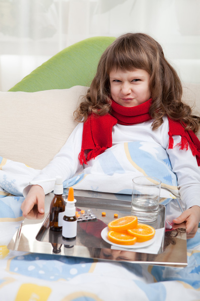 Маленька хвора дівчинка з шарфом у ліжку приймає ліки
 - Фото, зображення