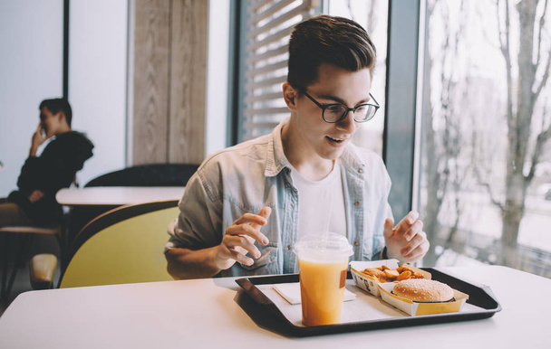 Handsome young man having lunch in cafe alone - 写真・画像