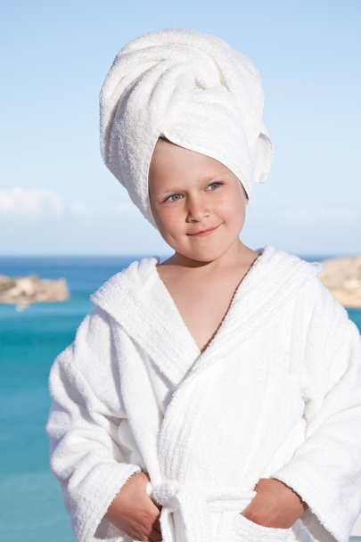κοριτσάκι με πετσέτα στο κεφάλι σε λευκό μπουρνούζι στη θάλασσα backgro - Φωτογραφία, εικόνα