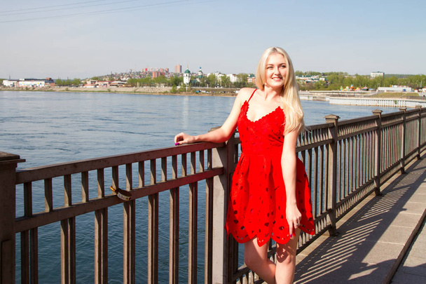 Blonde in a short summer dress on the bank of the Angara River in Irkutsk - Photo, image