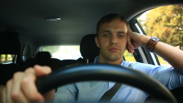 Ένας άνδρας οδηγεί ένα αυτοκίνητο, ένας άνδρας οδηγεί στο αυτοκίνητο στους δρόμους της πόλης και χαρούμενα φλυαρίες με τον επιβάτη, γελώντας. Ο τύπος πίσω από το τιμόνι - Πλάνα, βίντεο