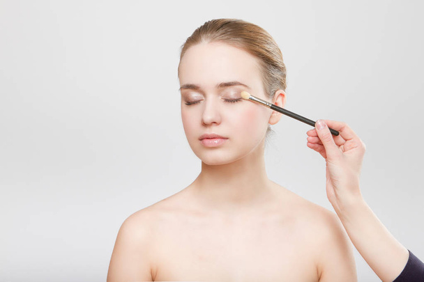 Beautiful woman face close up studio on grey makeup process - Photo, image