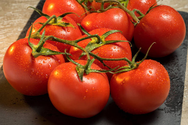 Trauben roter reifer nasser Tomaten auf dem Tisch - Foto, Bild