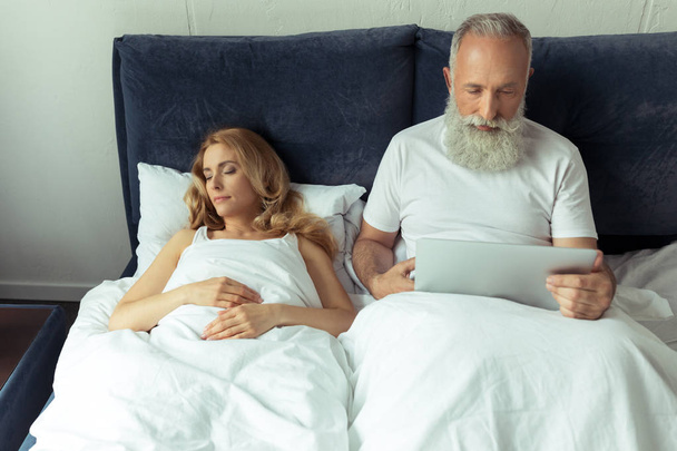 Mature couple in bed with laptop  - Valokuva, kuva