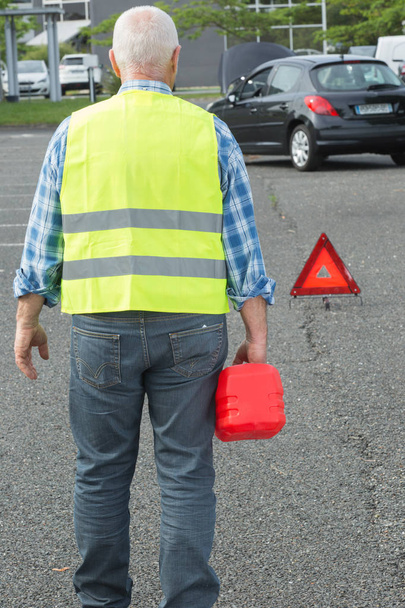 senior aged man holding gas can to refill his car - Fotoğraf, Görsel