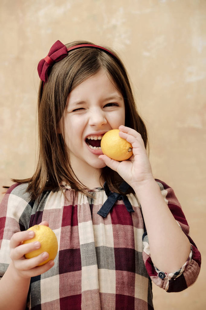 kid or girl with winking eye eating lemons - Foto, Bild