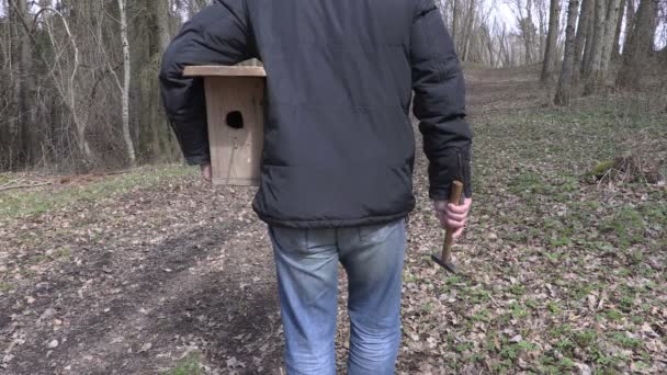 Man with birdhouse and hammer on path in the park - Footage, Video