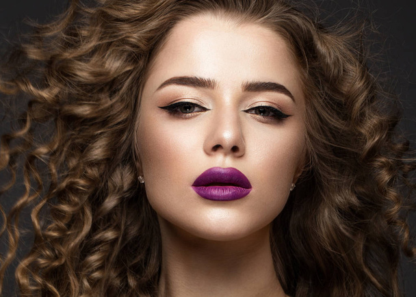 Beautiful brunette girl in move with a perfectly curly hair, and classic make-up. Beauty face. - Foto, Bild
