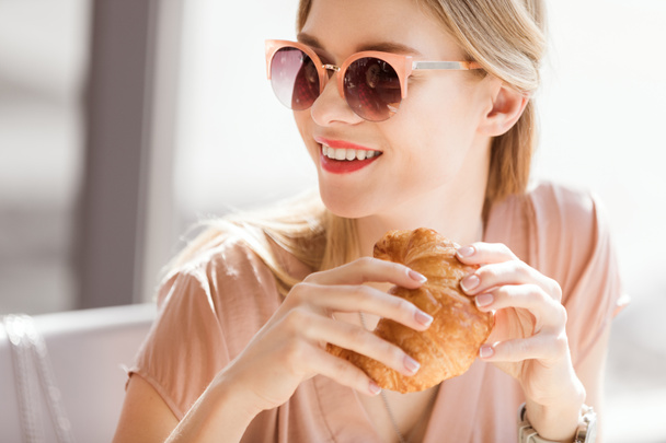 Nuori nainen syö croissant
 - Valokuva, kuva