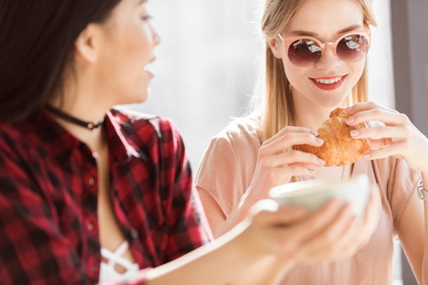 chicas comiendo croissants y tomando café
 - Foto, Imagen