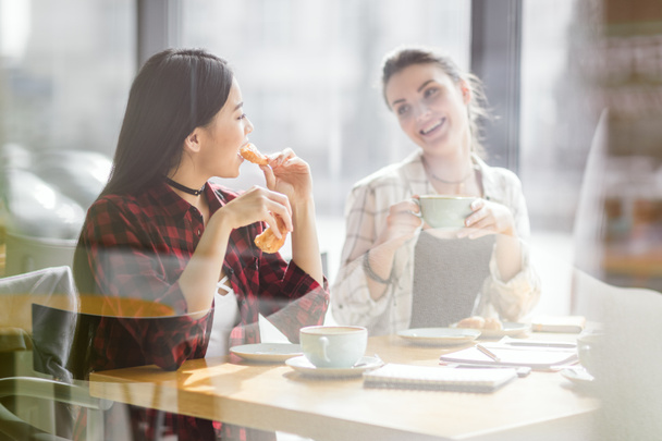 chicas comiendo croissants y tomando café
 - Foto, Imagen